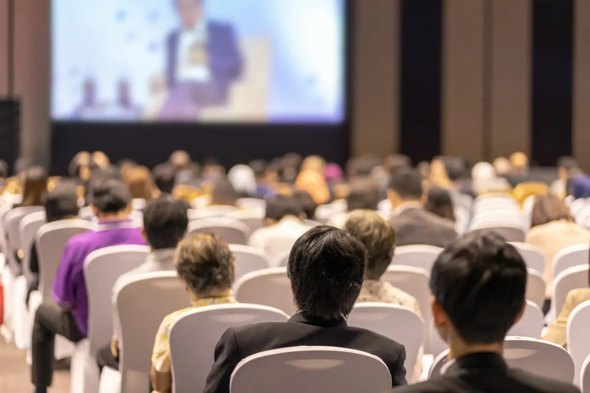 Rear view of Audience listening Speakers on the stage in the con – United Outcomes – United Outcomes Audience listening Speakers on the stage in a conference hall or seminar meeting